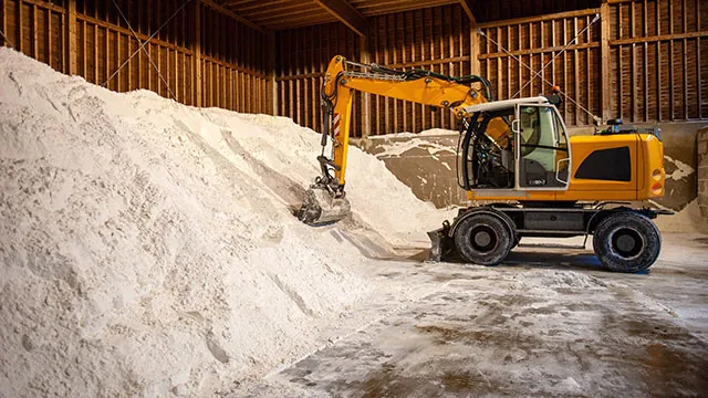 excavator picking up salt in a salt storage