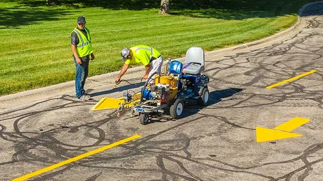 plm paving employees painting arrows in the road