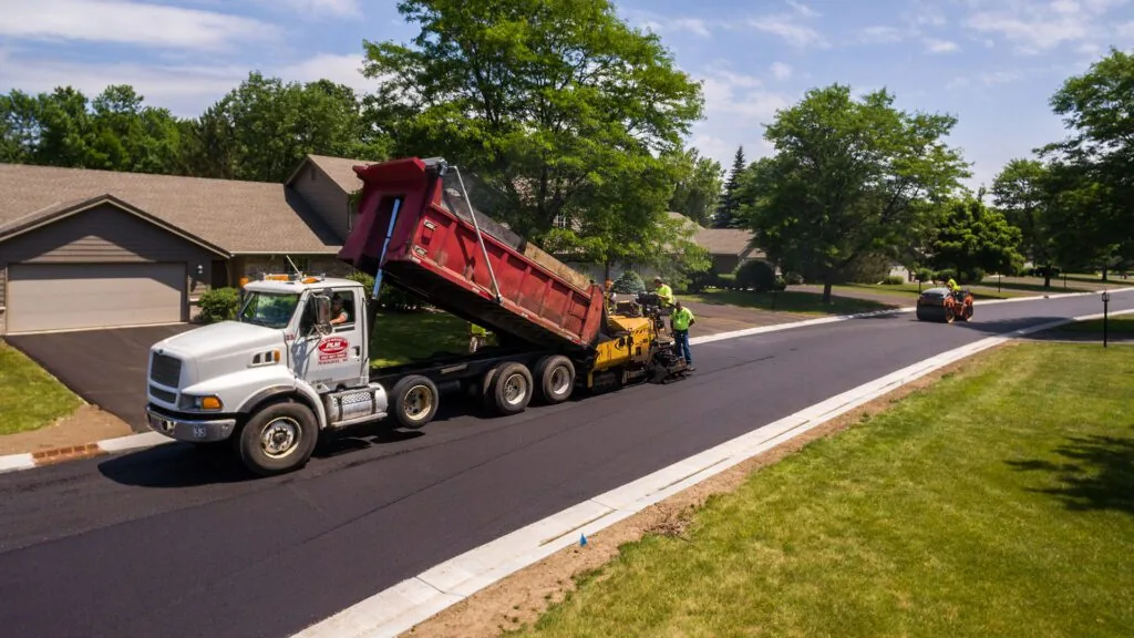 plm paving dump truck in front of a suburban house