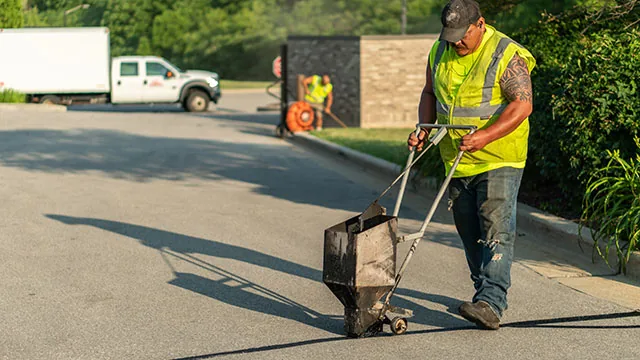 plm paving employee filling in a crack in the pavement