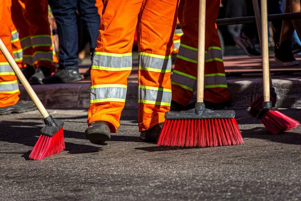 close up of brooms and feet of street sweepers
