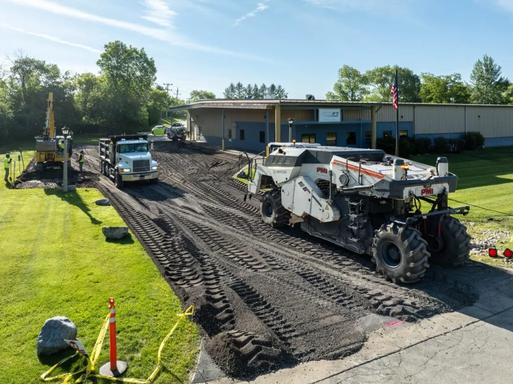 dug up driveway with plm paving trucks on it