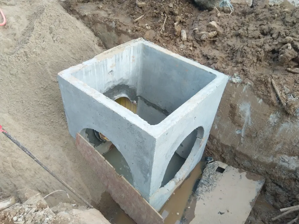 Concrete encased catch basin being built in construction area.