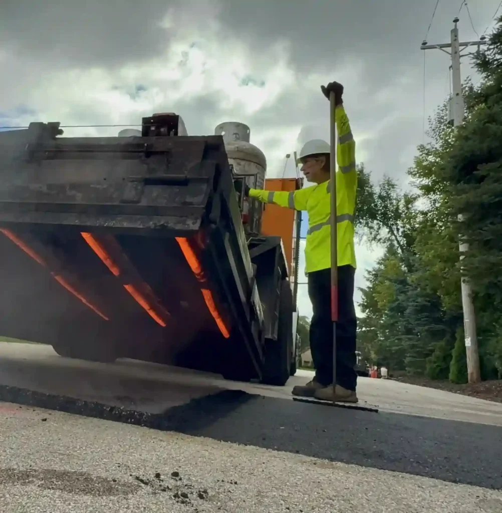 PLM worker using an asphalt patching machine