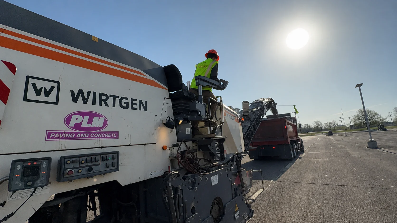 PLM worker operating a Wirtgen milling machine beside a dump truck at Milwaukee Tool