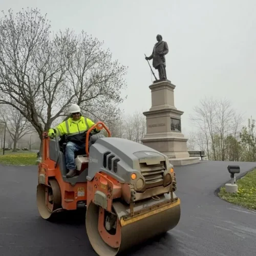 PLM employee compacting the fresh asphalt with a hot roller at Juneau Park.