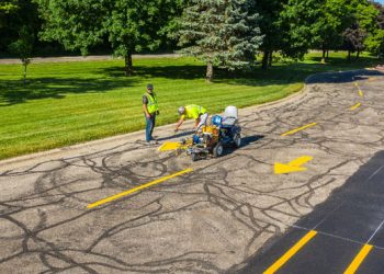 plm paving employees painting a yellow arrow in the road